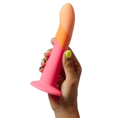 Vibrador de silicone em três tons segurado por uma mão.