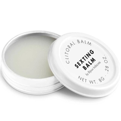 Pote branco de bálsamo clitoriano com tampa com texto e bálsamo claro dentro.