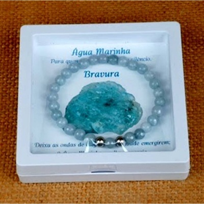 Pulseira de contas azuis em embalagem branca com pedra azul e texto em português