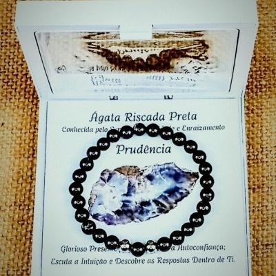 Pulseira de contas negras com cartão explicativo de Ágata Riscada Preta, dentro de caixa branca.