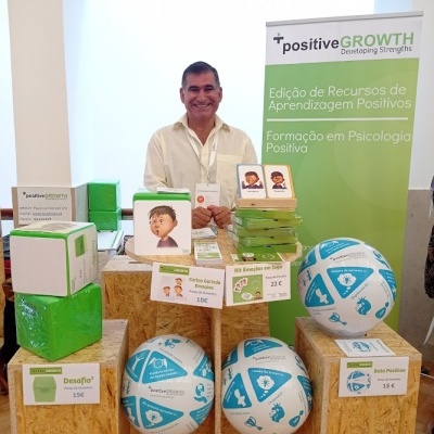 Expositor de produtos com bolas azuis e brancas, caixas verdes, cartões ilustrados e banner sobre Psicologia Positiva