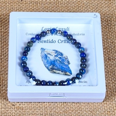 Pulseira azul de contas esféricas numa caixa branca sobre fundo de juta