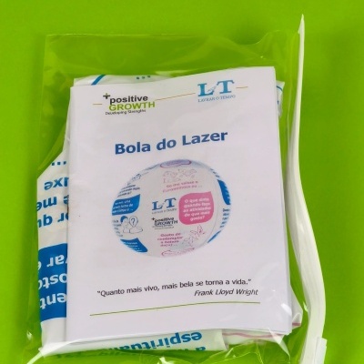 Saco plástico transparente com produto Bola do Lazer com etiqueta branca sobre fundo verde