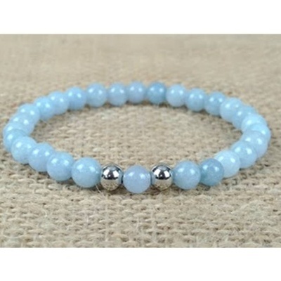 Pulseira de contas azul claro e prateadas sobre tecido bege