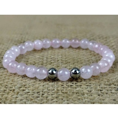 Pulseira de contas rosa translúcidas com duas contas prateadas sobre tecido bege