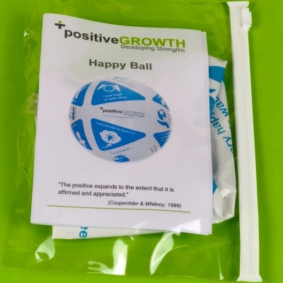 Embalagem transparente com produto Happy Ball da positiveGROWTH sobre fundo verde