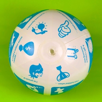 Bola insuflável branca e azul com desenhos e frases em inglês sobre fundo verde