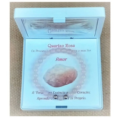 Pulseira de quartzo rosa dentro de caixa branca com texto em português sobre amor