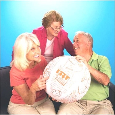 Três idosos seguram uma grande bola branca com desenhos castanhos