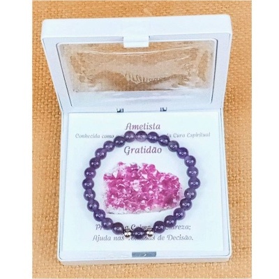 Pulseira de ametista roxa num estojo branco com etiqueta informativa e cristais rosa