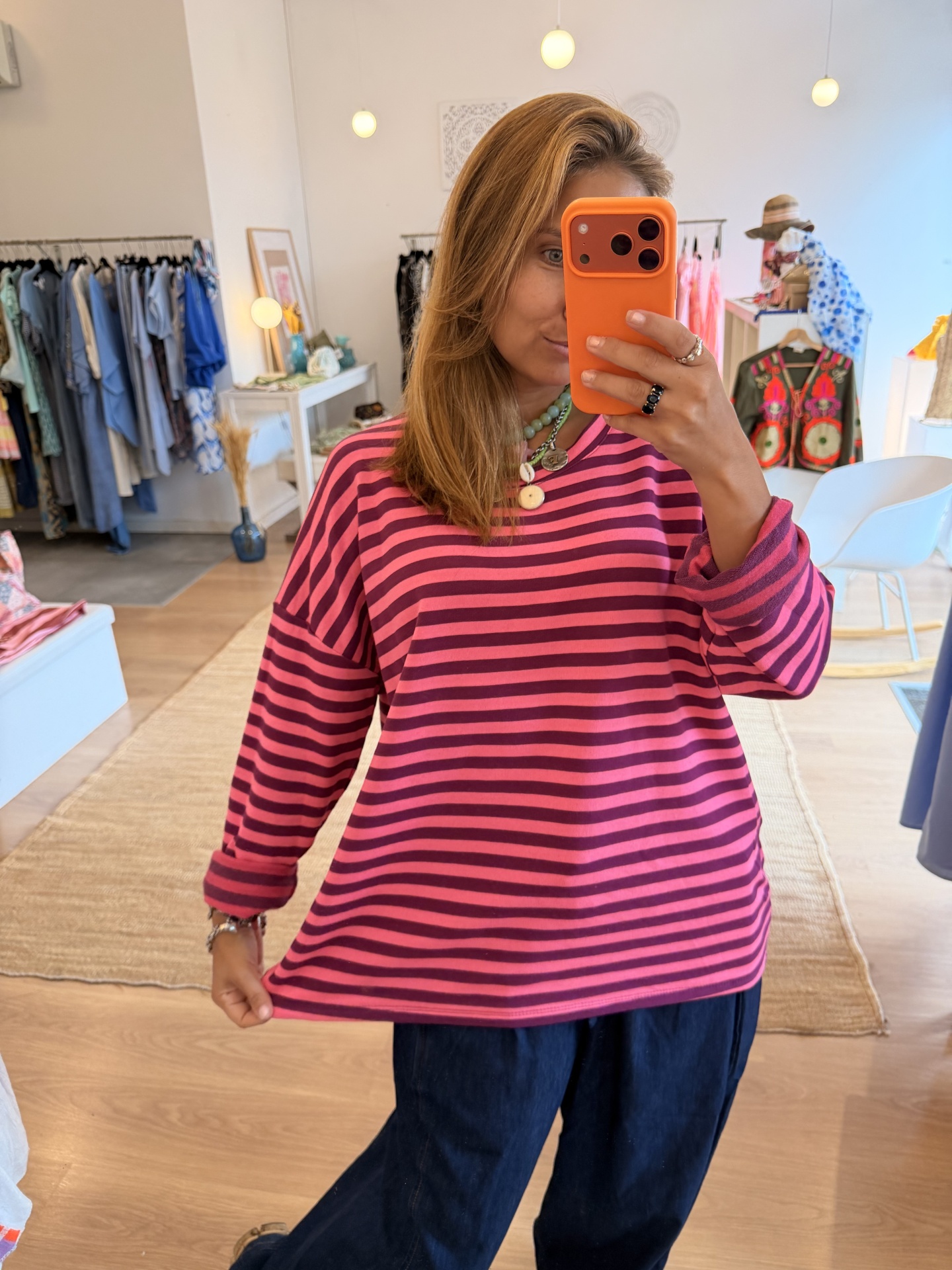 Camisola Riscas Camisola de riscas rosa e vermelhas em pessoa numa loja de roupa