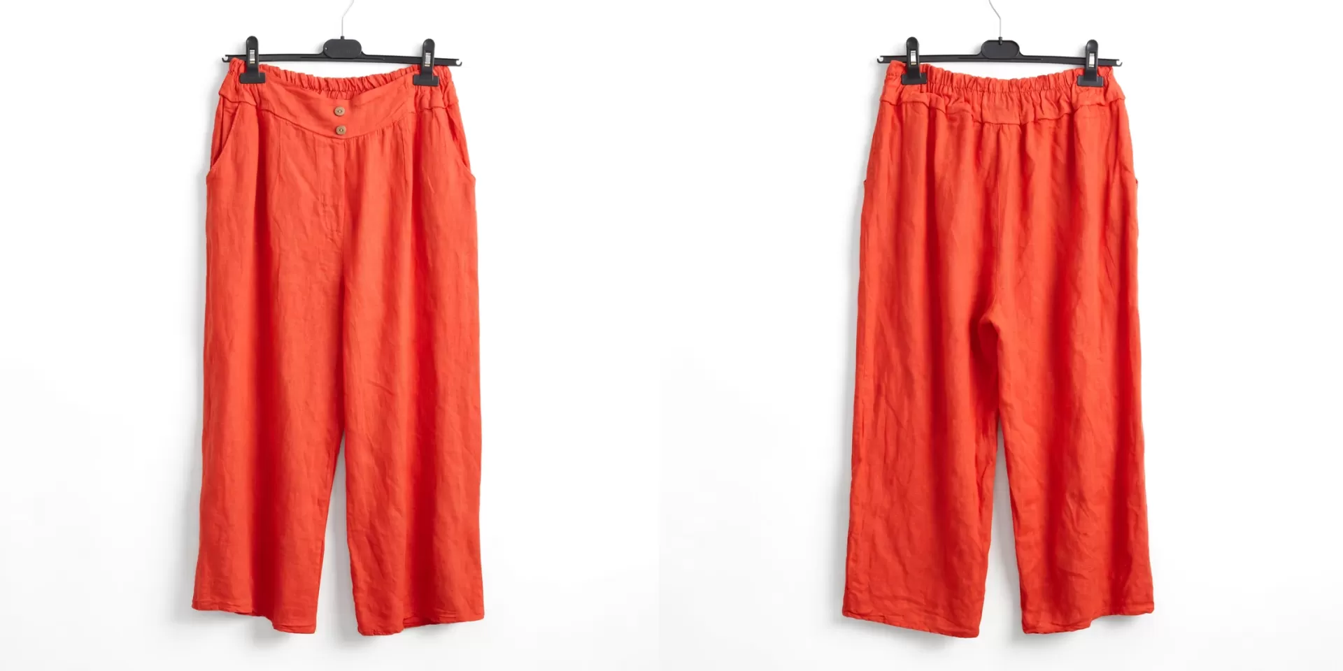 Conjunto Linho Summer Calças largas laranja com cintura elástica e botões, penduradas em cabides negros