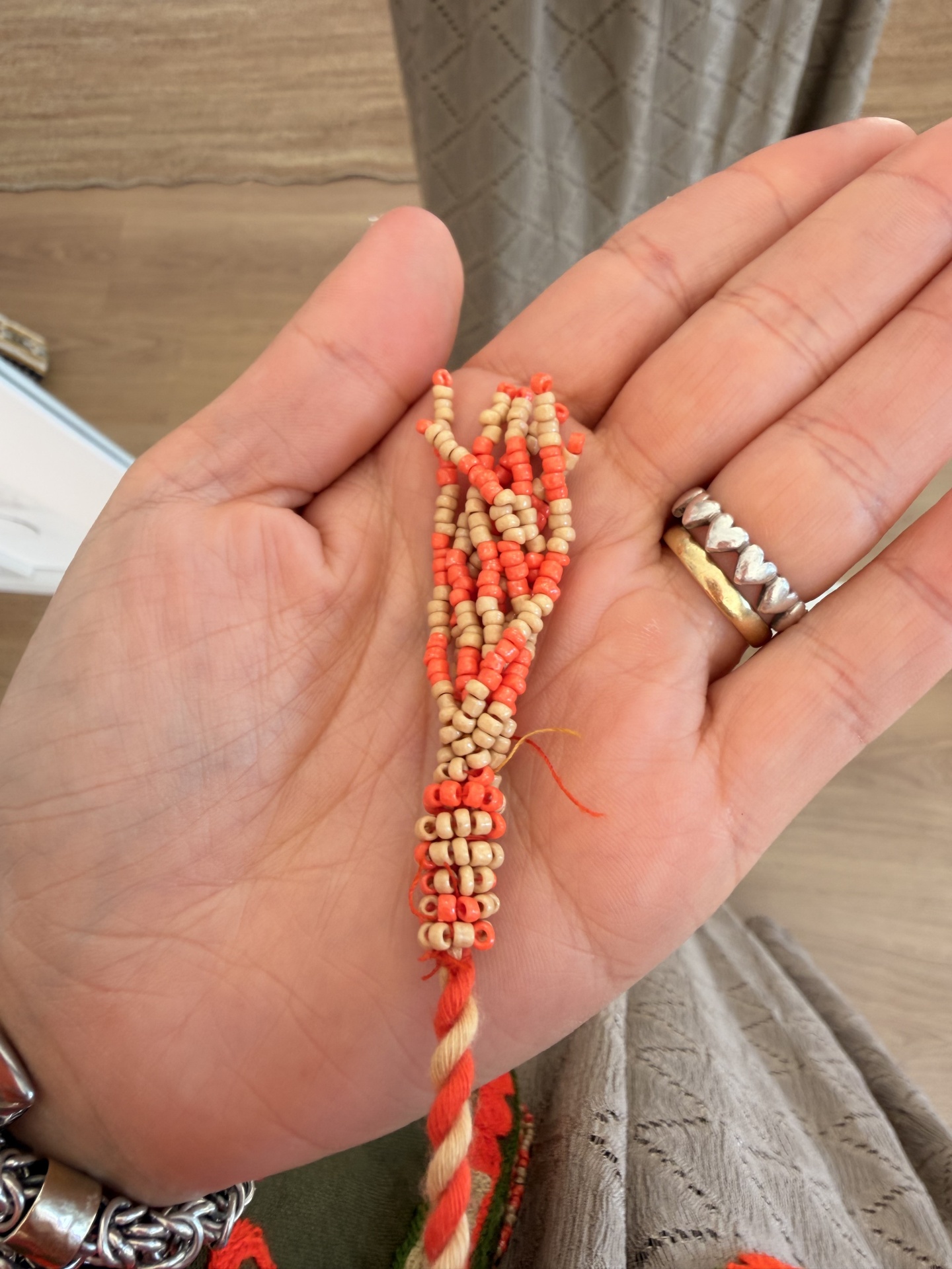Bolero Bordado Boho Pulseira de contas laranja e beje na mão com anéis