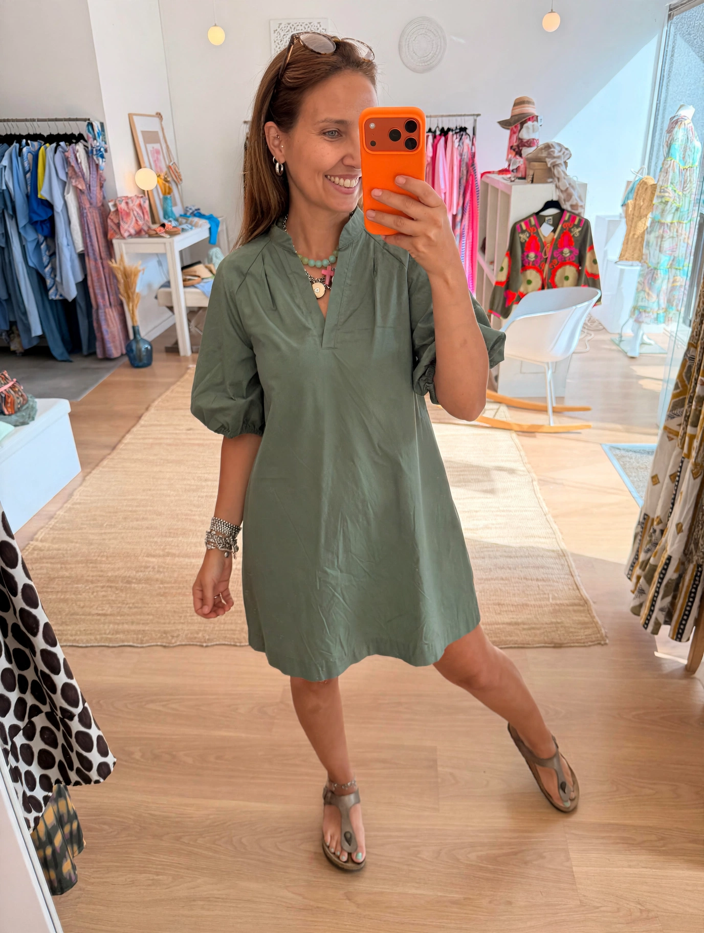 Vestido Lili Mulher tira selfie usando vestido verde com mangas bufantes em loja de roupas