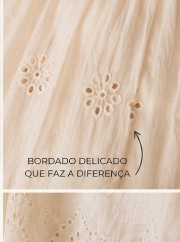 Vestido Encanto Tecido bege com bordados delicados em padrão floral e texto BORDADO DELICADO QUE FAZ A DIFERENÇA.