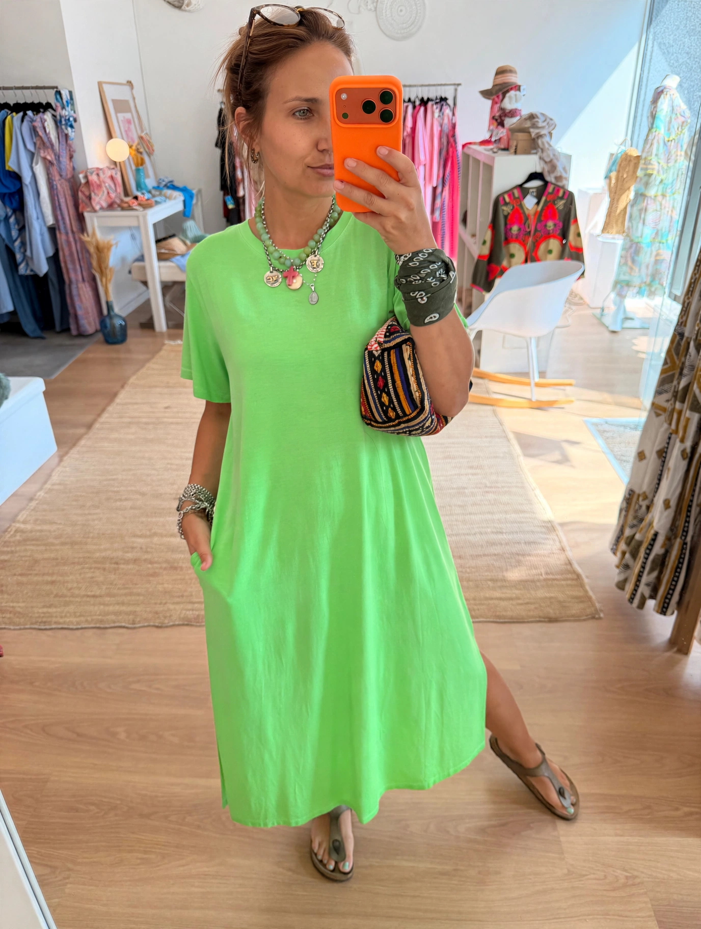 Vestido T-shirt Decote redondo Mulher com vestido verde-limão a tirar selfie em loja de roupas.
