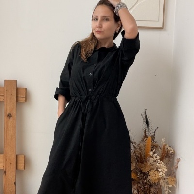 Mulher com vestido preto assimétrico e botas pretas com decoração interior minimalista
