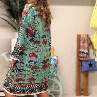 Vestido verde água com padrão de peixes coloridos e sandálias pretas.