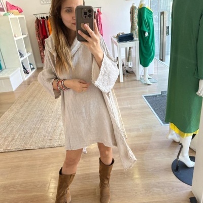 Vestido bege claro com mangas largas e cinto, botas castanhas de camurça, em loja de roupa