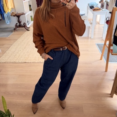 Mulher com camisola castanha e calças azuis a tirar selfie em loja