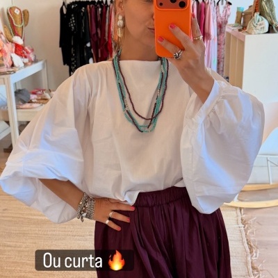 Blusa branca de manga larga em ambiente de loja de roupas