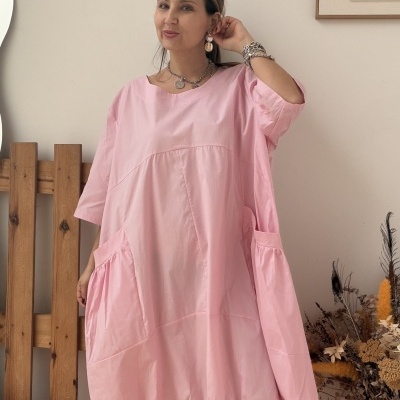 Vestido rosa com bolsos laterais e elástico na bainha em ambiente interior com decorações