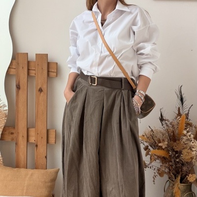 Mulher com camisa branca e saia longa cinza em interior decorado