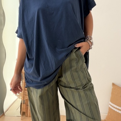 Pessoa com camisola azul escura e calças verdes às riscas com acessórios, em ambiente interior