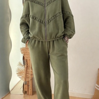 Conjunto desportivo verde-oliva com casaco e calças largas, e ténis brancos com detalhes dourados