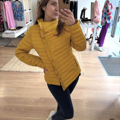 Mulher com casaco amarelo matelassê numa loja de roupa
