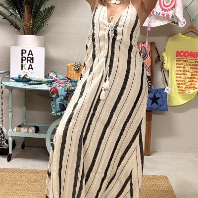 Vestido comprido bege com riscas pretas e brancas usado por mulher