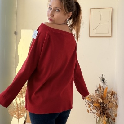 Mulher de costas vestindo camisola vermelha de malha com etiqueta branca no ombro