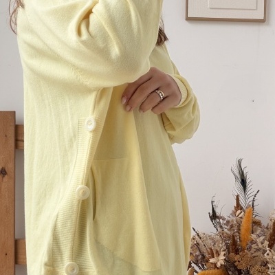 Camisola amarela clara com botões e bolso frontal usada por mulher em ambiente interior