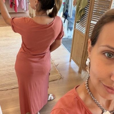 Vestido cor de ferrugem com manga curta usado por mulher numa loja de roupas