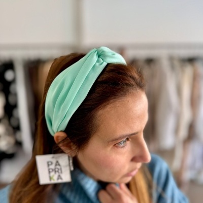 Mulher com faixa verde água e etiqueta PAPRIKA na cabeça