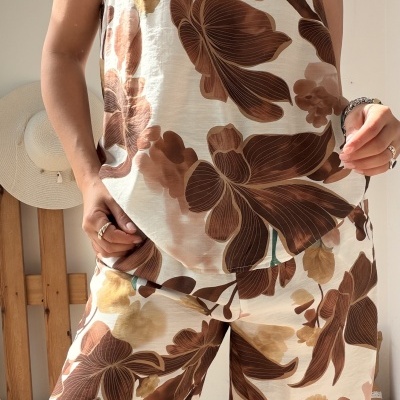 Conjunto de roupa feminina floral em tons castanho e bege, roupa casual com acessórios dourados e prateados.
