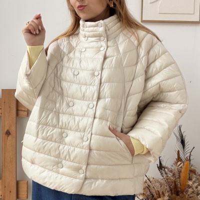 Casaco acolchoado creme com botões e gola alta usado por mulher