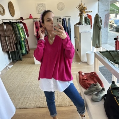 Mulher na loja com camisola rosa fúcsia, camisa branca, calças azuis e ténis bege