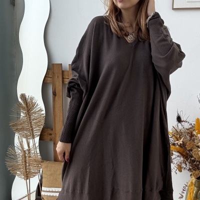 Mulher com vestido castanho escuro e botas bege em ambiente interior decorado