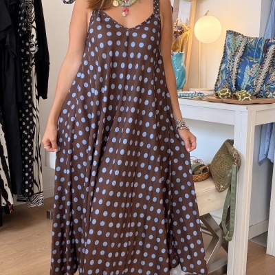 Vestido castanho com bolas azuis em modelo feminino com alças em laço, cenário interior com móveis e chapéu