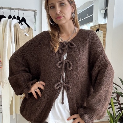 Mulher com cárdigan castanho de malha grossa e calças com bolinhas brancas