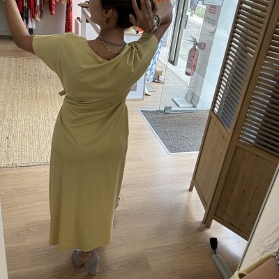 Vestido midi amarelo em loja de roupa com mulher a tirar selfie de costas