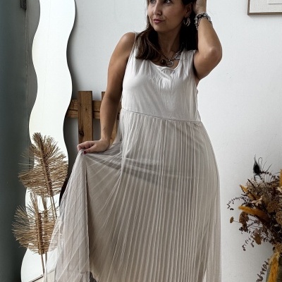 Vestido branco comprido com saia plissada translúcida e botas castanhas dentro de casa