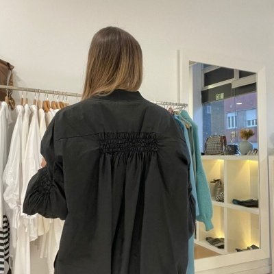 Casaco preto com pregas elásticas nas costas e mangas numa loja