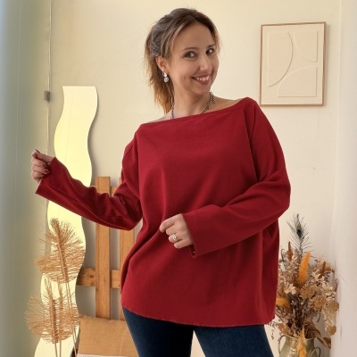 Mulher a usar camisola vermelha e jeans num ambiente interior decorado