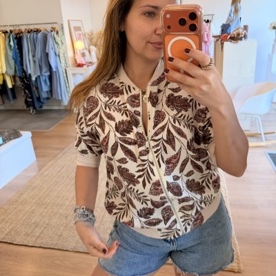 Camisola curta com padrão de folhas castanhas e creme com calções jeans azuis desfiados.