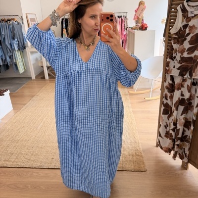 Vestido azul xadrez com mangas compridas e decote em V em loja de roupa