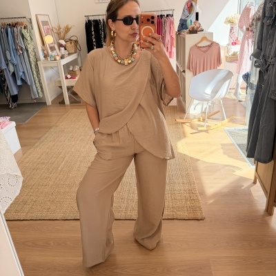 Mulher a tirar selfie num espelho com roupa bege e acessórios coloridos numa loja de roupa