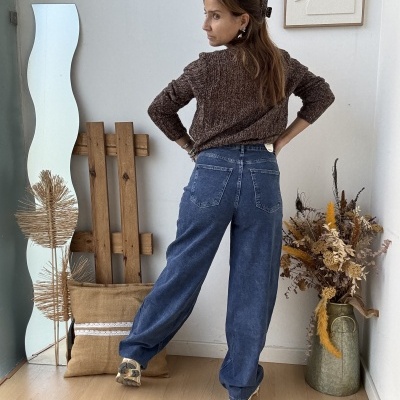 Mulher de costas com camisola castanha e calças de ganga azuis largas