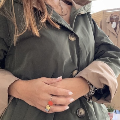 Casaco impermeável verde escuro com interior bege e botões grandes.